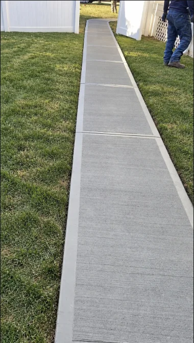 Concrete walkway with defined edges between two strips of grass.
