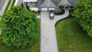 Aerial view of a curved paver driveway and landscaped front yard.