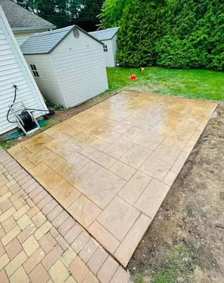 Small tan patio beside a house and an adjoining paver path.