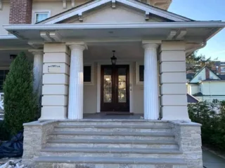 Stone entrance steps beneath a porch with white columns.