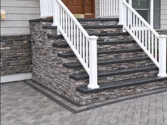 Stone-faced front steps with dark treads and white railings.